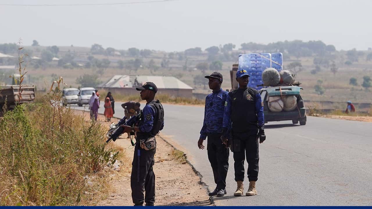 Armed police stand guard at rural roadside security checkpoint