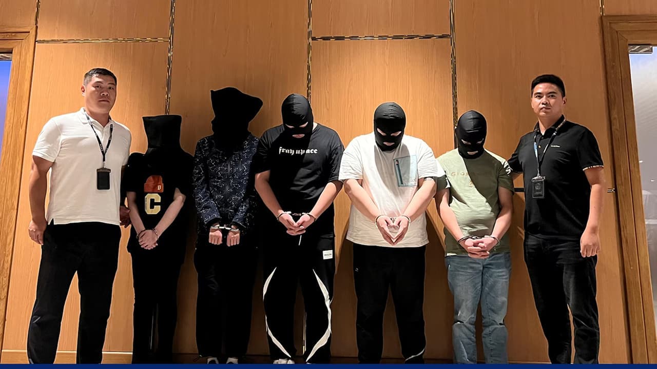 Police stand beside masked suspects detained during indoor arrest operation