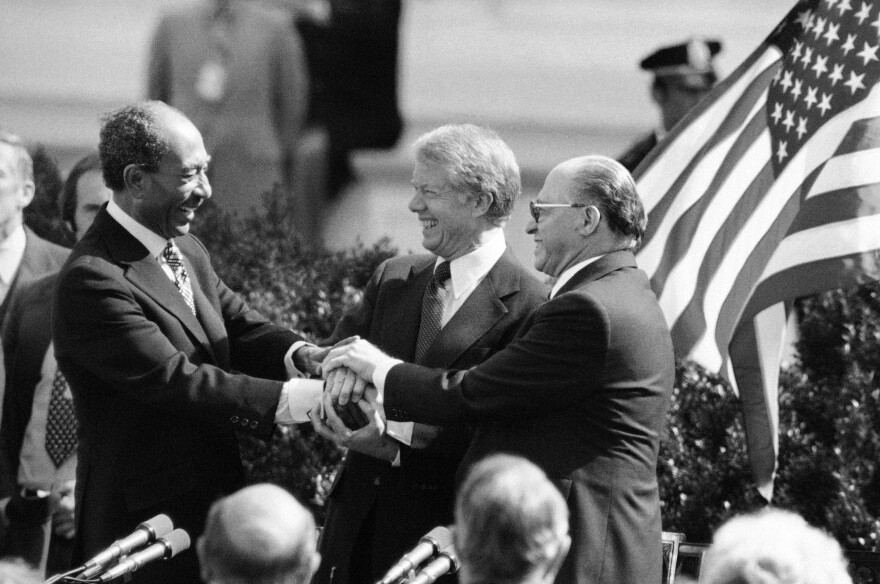 Egyptian President Anwar Sadat, left, President Jimmy Carter, center, and Israeli Prime Minister Menachem Begin clasp hands to symbolize their agreement after signing the Middle East Peace Treaty at the White House in Washington, March 27, 1979.